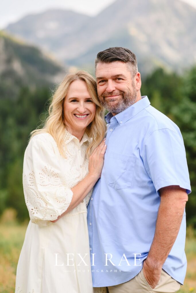 Utah couple posing for a photo in Park City. Man has hand in his pocket. Women is leaned in with hand on mans chest. 