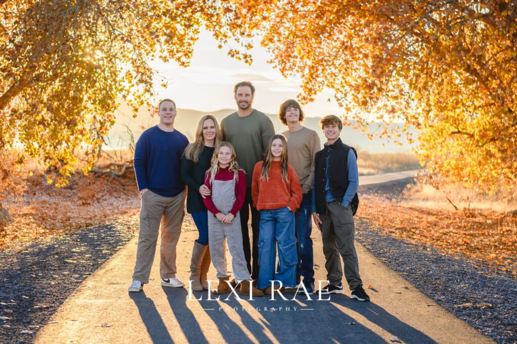 Family standing in Utah fall leaves posing for a photograph. 