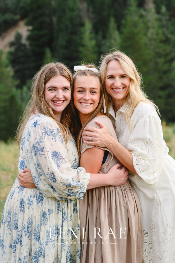 Mom and two daughters posing for a photo. They had their arms wrapped around each other. 