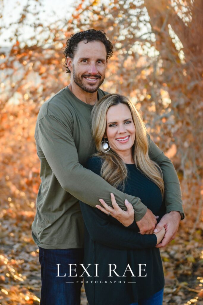 Married couple hugging in front of Fall leaves 