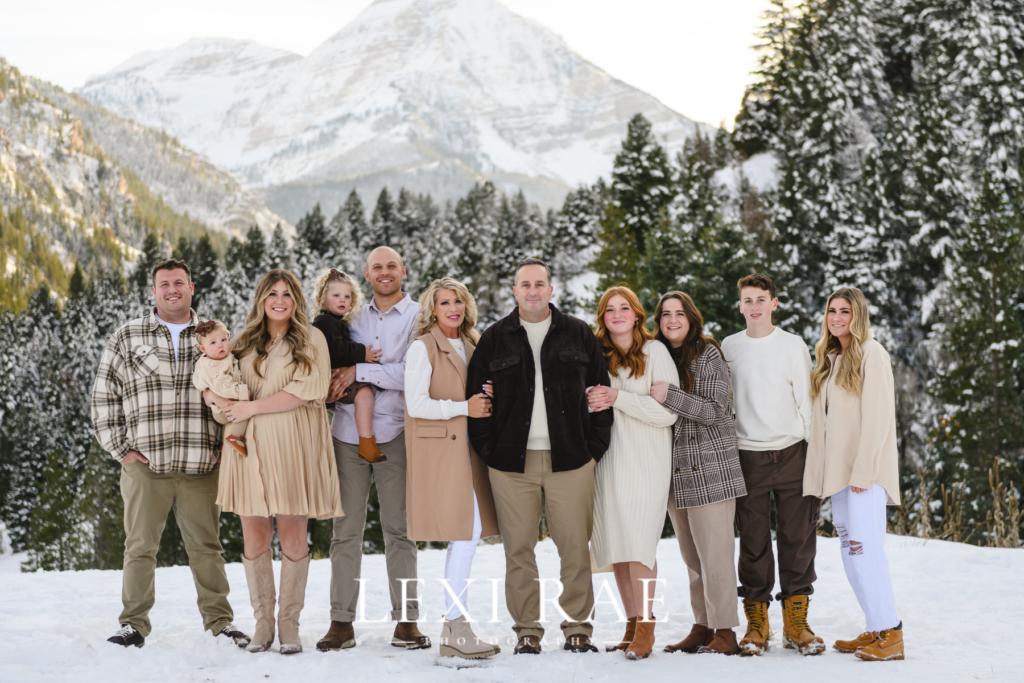 Large extended family photo up in the Utah mountains. Family is wearing comfortable and cozy winter outerwear of layers and coats. 