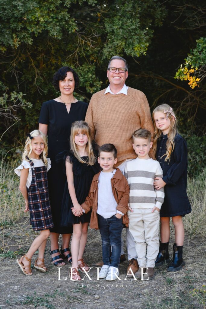 Extended family grouped together in Utah County. Wearing a classic color palette of whites, creams, camel, brown and black. 